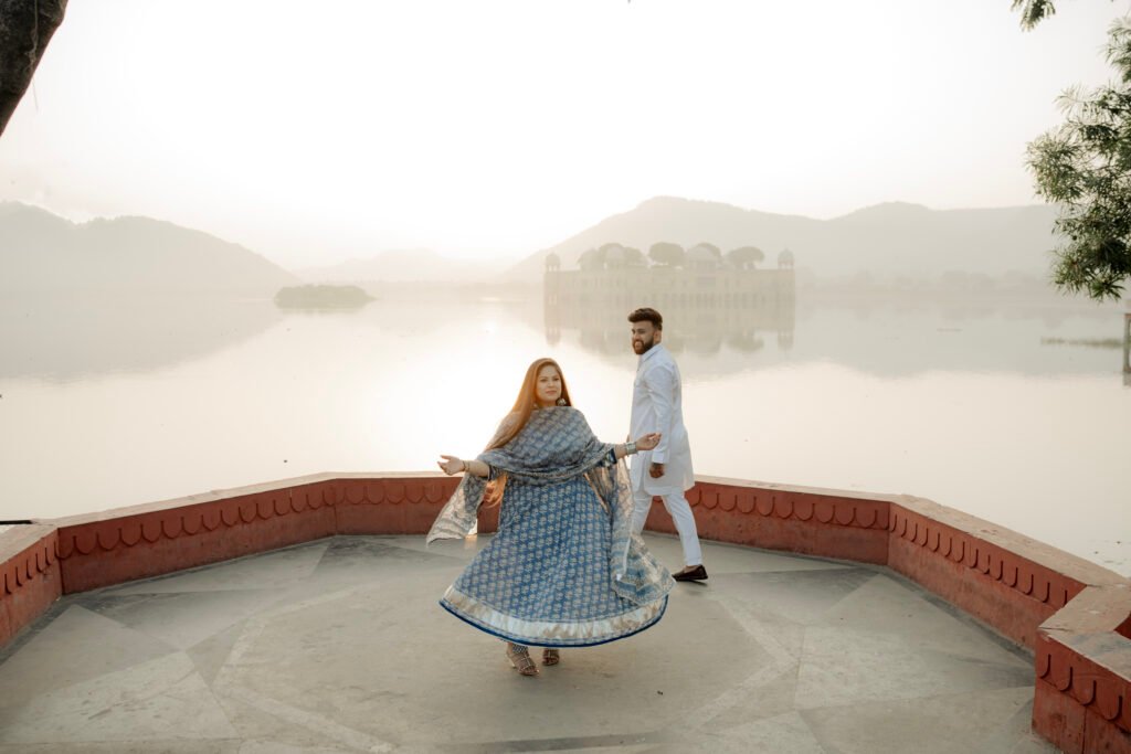 A happy bride-to-be twirling in a blue ethnic dress during her Jal Mahal pre-wedding photoshoot in Jaipur.